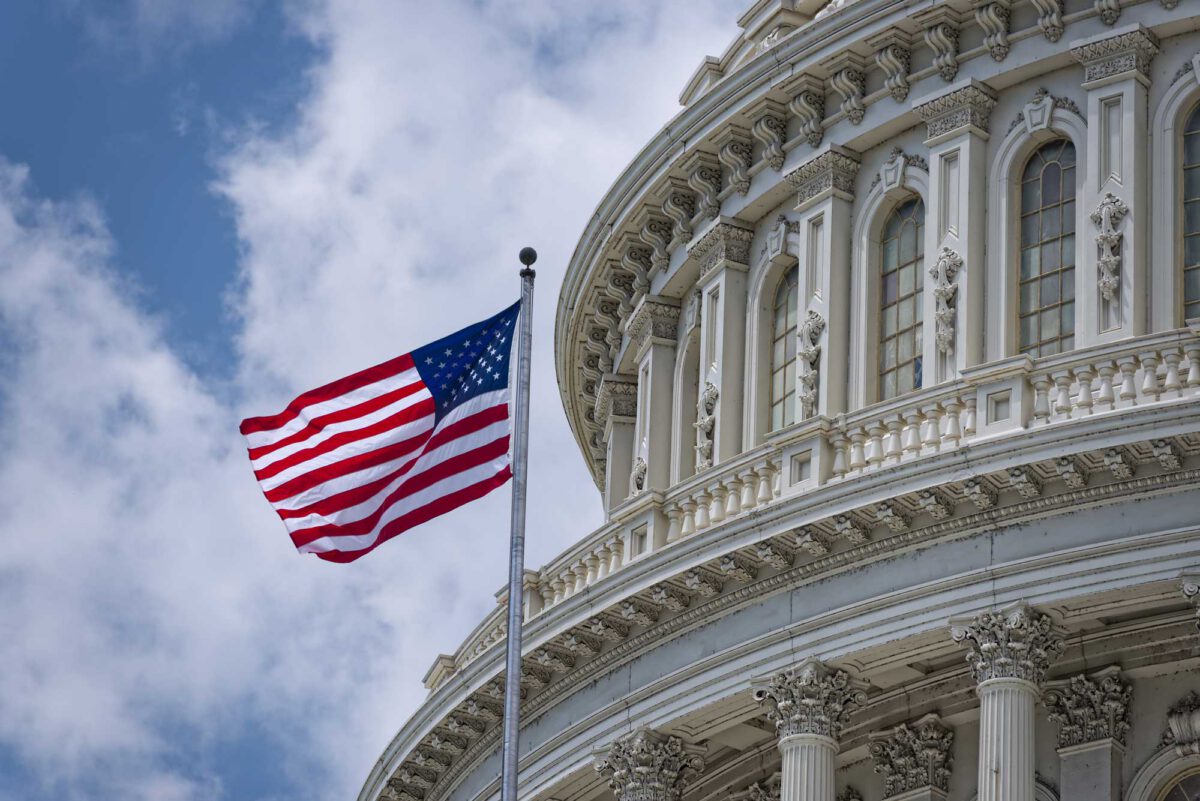 The American flag in front of a closeup of the US Capitol rotunda from the outside